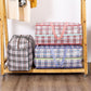 Three large checkered luggage bags in black, red, and blue with robust handles and a wide opening, displayed on a wooden rack.